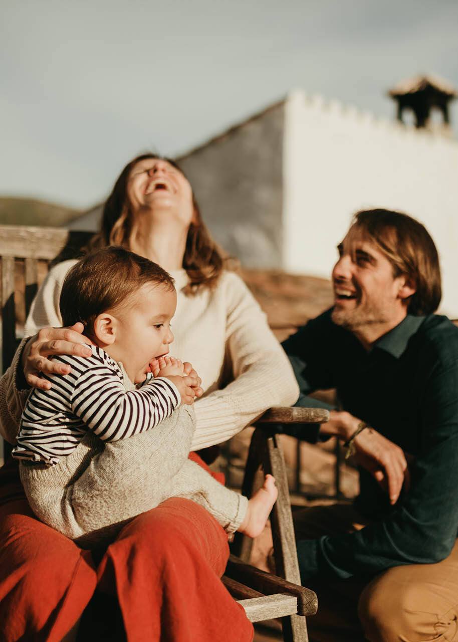 Parents laughing with baby trying to eat his foot